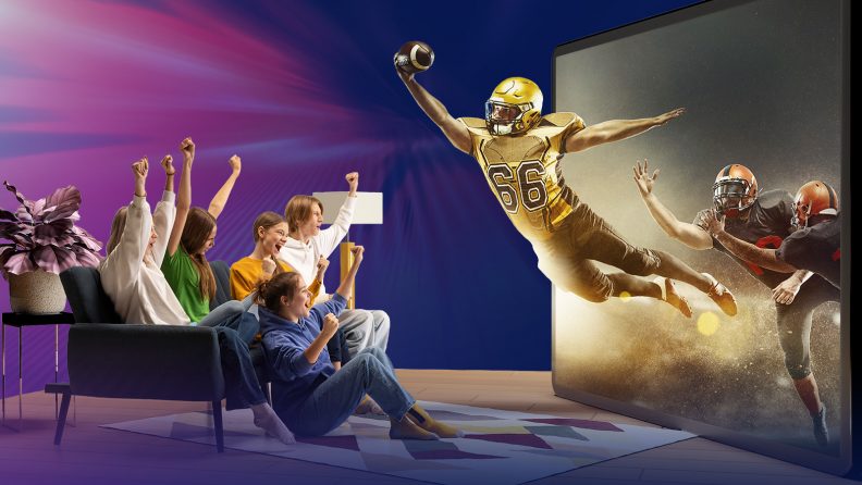 A household group watching an immersive Connected TV experience on a large screen, with a live sports broadcast extending beyond the screen into the living room